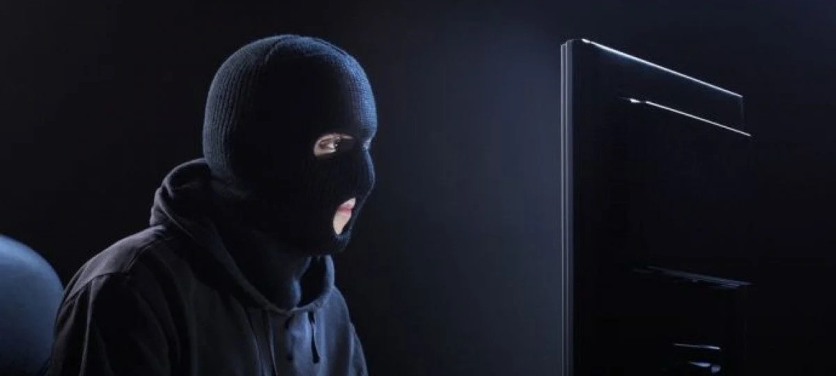 Мужчина в балаклаве сидит за компьютером