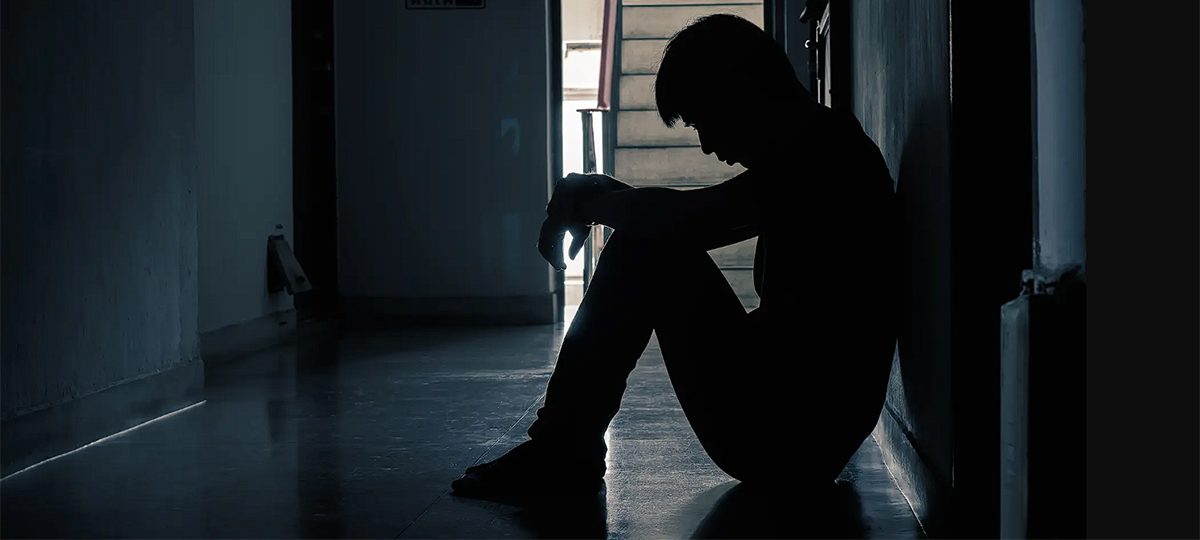 молодой человек сидит в углу коридора